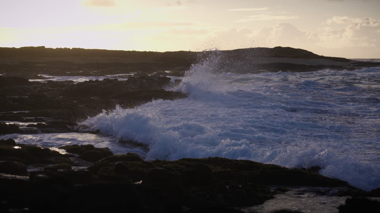 A reflective man sits on rugged rocks near the sea as waves break and sunlight fades, capturing a moment of mindfulness, solitude, and harmony with nature’s motion