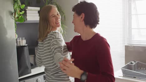 Caucasian-lesbian-couple-dancing-together-in-the-kitchen-at-home