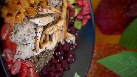 vertical panning close up of a healthy high protein bowl with sweet potato beet lentils rice chicken breast and tomatoes