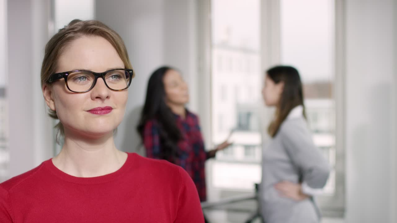 una mujer joven con una camiseta roja está escuchando y sonriendo durante una entrevista en la nueva oficina