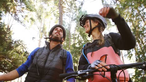 pareja de ciclismo de montaña apuntando a la naturaleza
