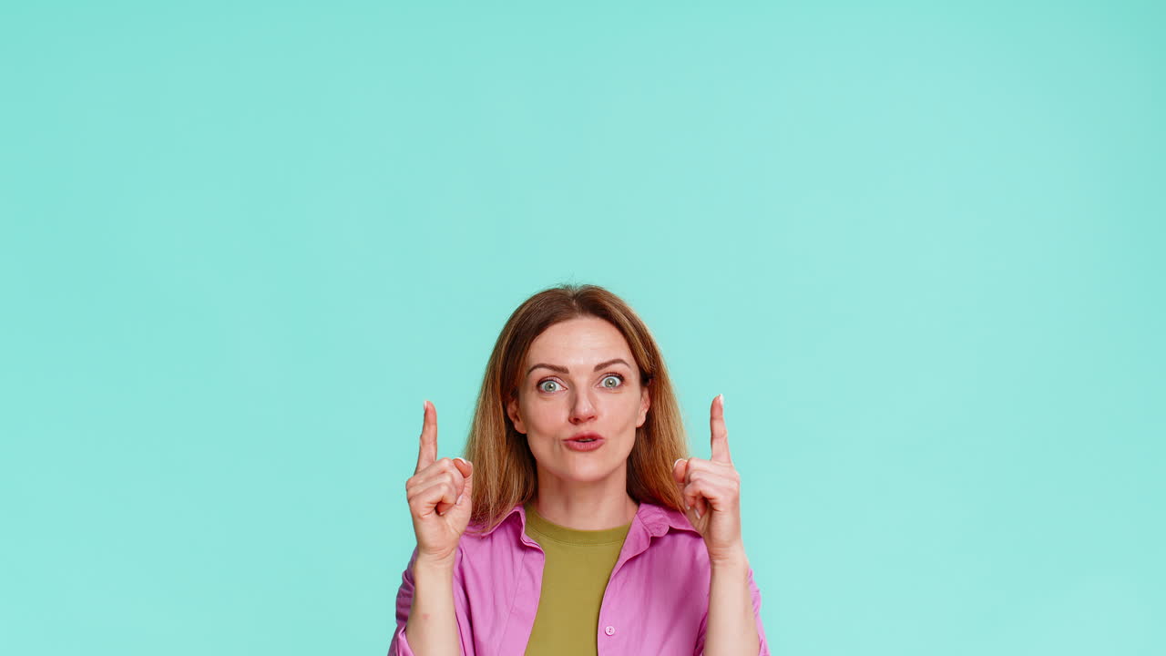 Woman pointing up with serious expression drawing attention to important thing or key information