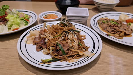 Beim-Abendessen-In-Einem-Restaurant-In-Bangkok,-Thailand,-Ein-Paar-Stränge-Gebratener-Nudeln-Mit-Einem-Paar-Stäbchen-Drehen