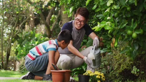 Happy-asian-father-and-son-in-garden,-planting-flowers-and-talking