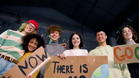 view from below of happy young environmental activists holding cardboard placards and looking at the camera