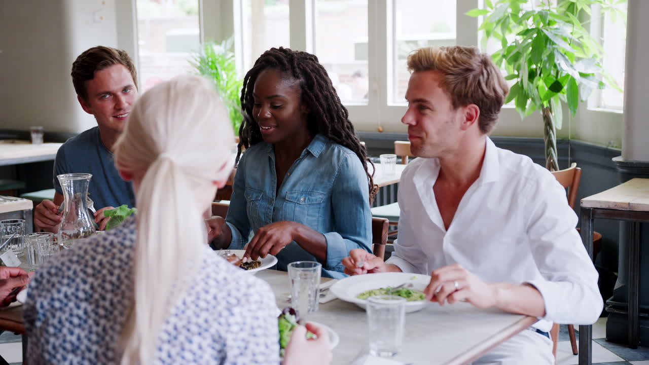 grupo de amigos jóvenes disfrutando de una comida en un restaurante juntos