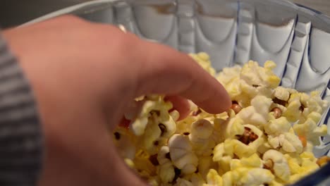 Close-up-static-shot-of-glass-bowl-filled-up-with-pop-corns-and-couple-reaching-out-for-it-enjoying-some-quality-time-together