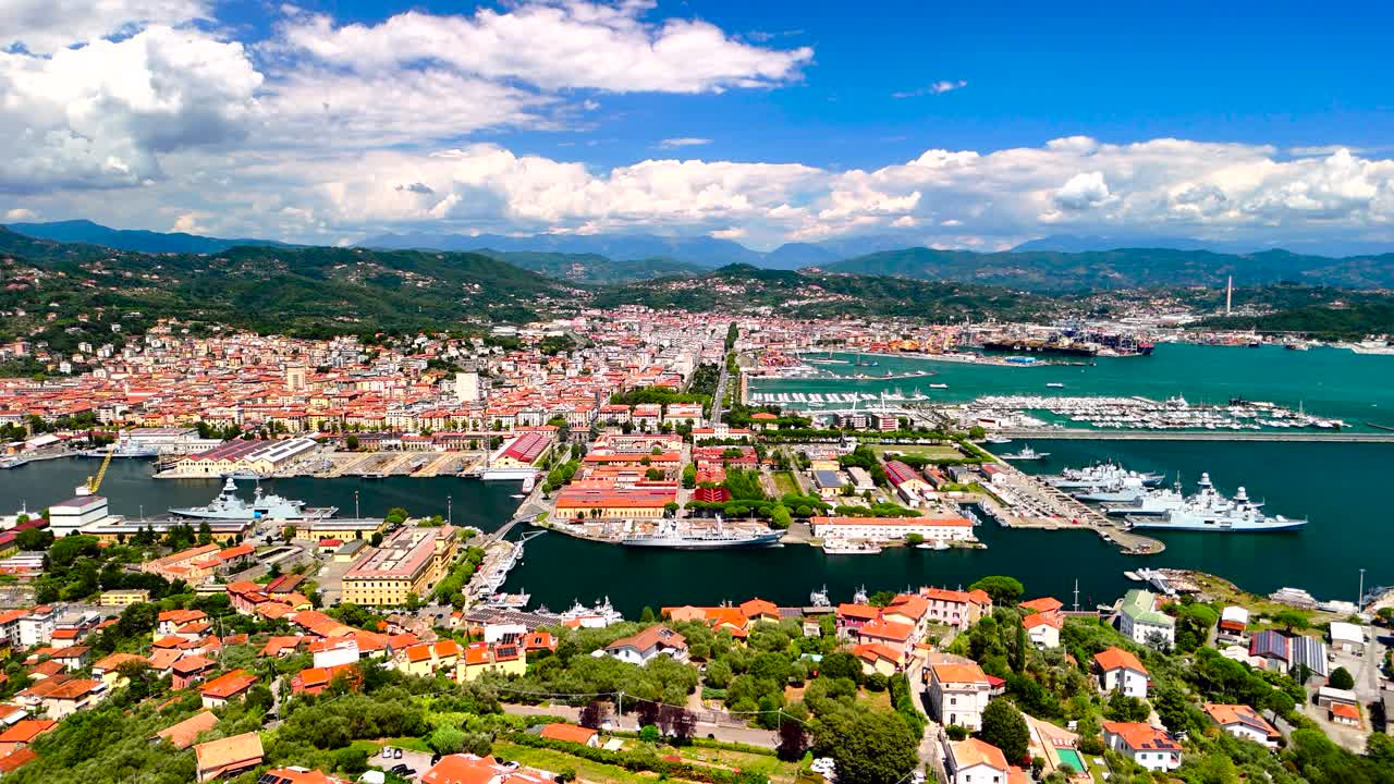 Stunning aerial view shows a lively coastal city with colorful buildings, a bustling harbor, and majestic mountains in the background. Enjoy the scenic beauty and waterfront activity
