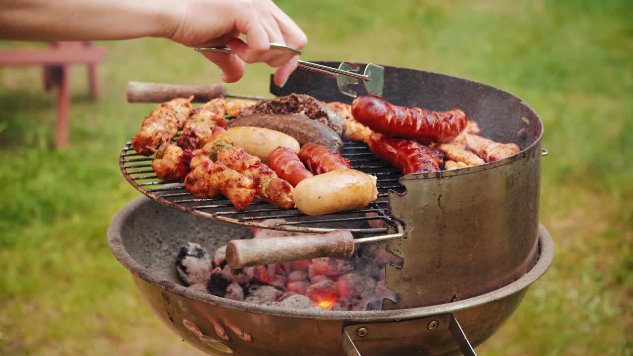 girare le salsicce alla griglia al barbecue