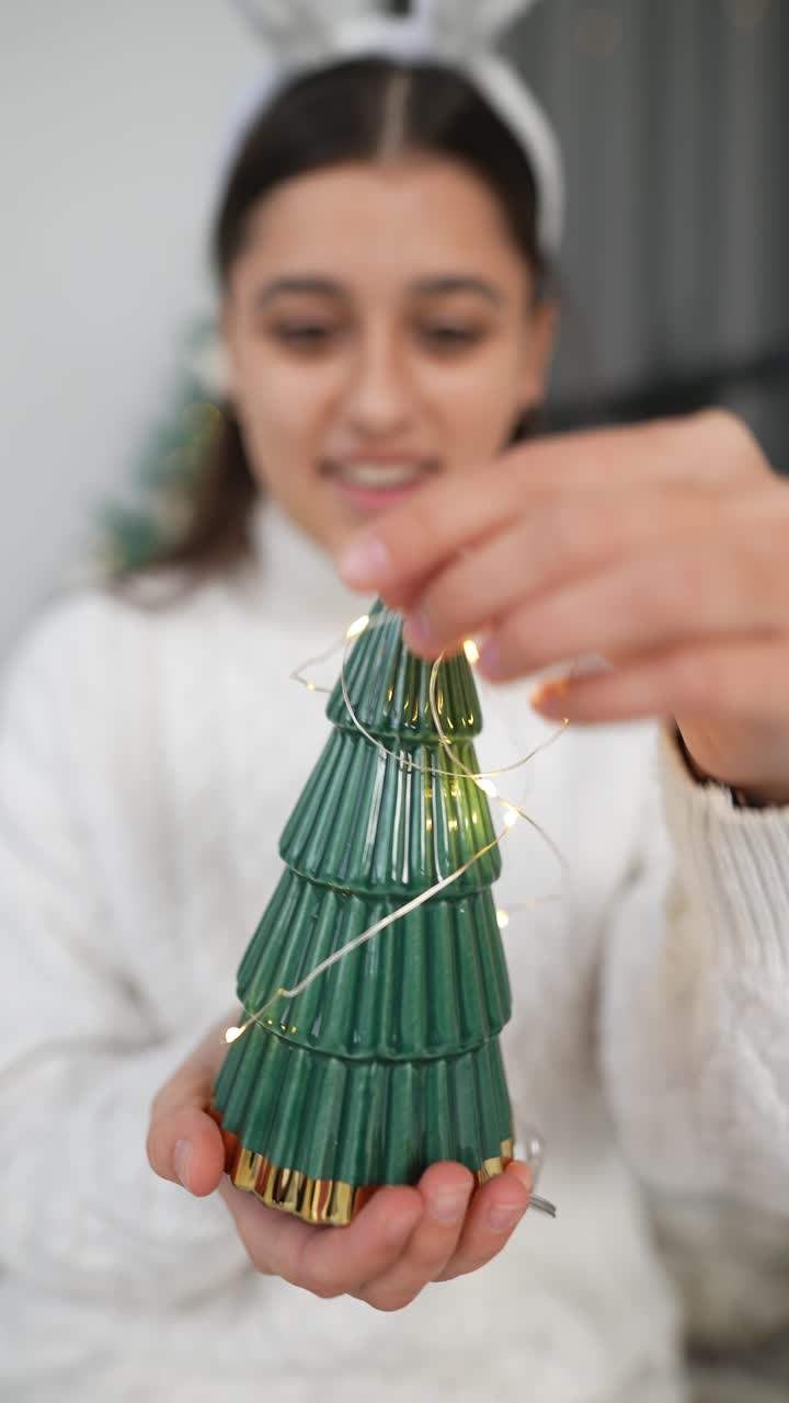 niña sosteniendo un árbol de navidad decorado con luces