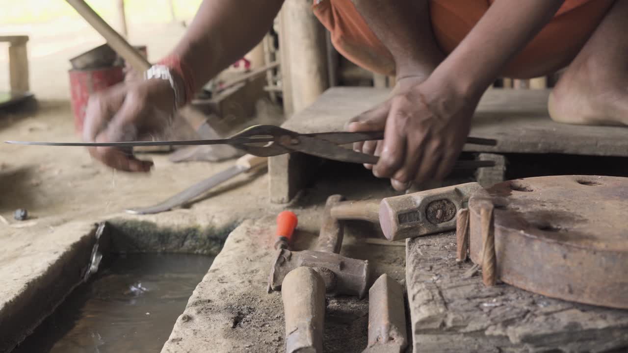 Quencing down heated shaped coconut knife by indian blackmsith