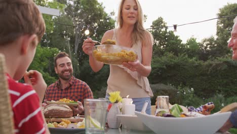 mujer joven sirviendo comida a los miembros de la familia al aire libre