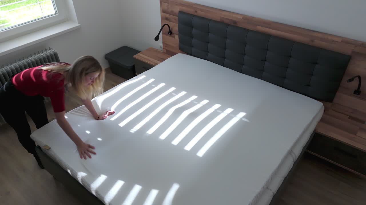 Woman installing a mattress topper to make her new bed more comfortable