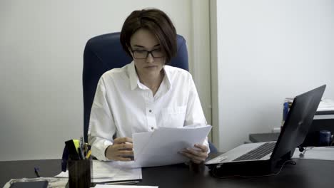 mujer leyendo documentos en la oficina