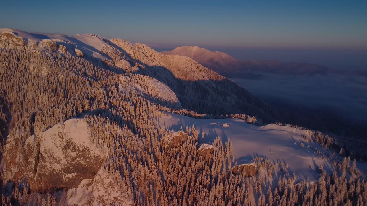 sumergirse en el impresionante paisaje invernal mientras el dron se desliza sobre los árboles cubiertos de nieve en el pico de la montaña, bajo un mar de nubes