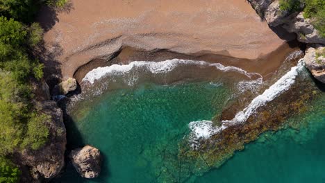 Drone-Se-Eleva-Sobre-Playa-Santu-Pretu-Playa-De-Arena-Negra-Con-Olas-Del-Océano-Rompiendo-En-Roca