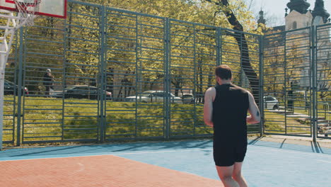 athletic man in sportswear playing basketball game successfully throws ball into the basket ring