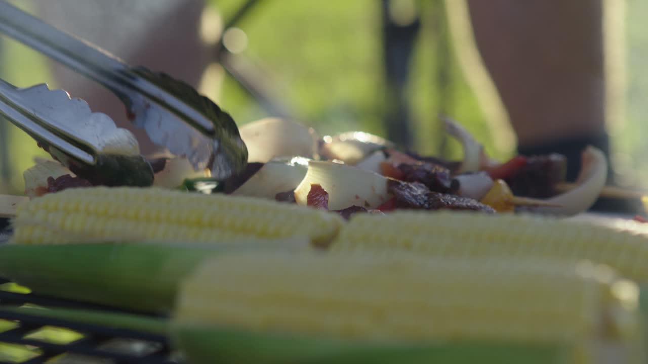 전경에 야채를 곁들인 바비큐 꼬치 뒤집기