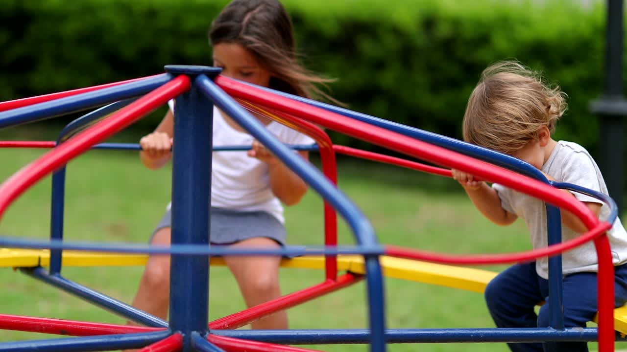 Niños jugando en un carrusel de parque infantil. Niños girando al aire libre