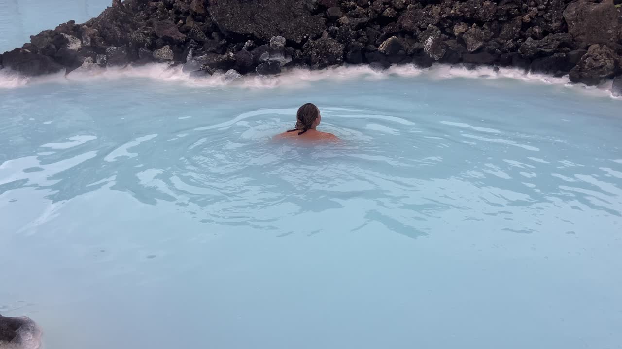 아름다운 여성이 화산 파란 물 온천 스파에서 행복하게 수영