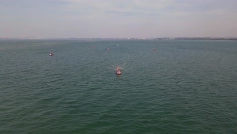 Reverse-aerial-footage-of-a-fishing-boat-together-with-others-at-sea-near-Pattaya-city-in-Thailand