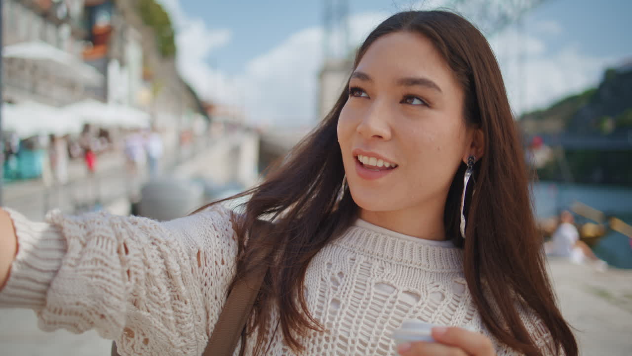 海辺の街でスマートフォンで写真を撮る楽しそうな少女のクローズアップ。自撮りをする女性。