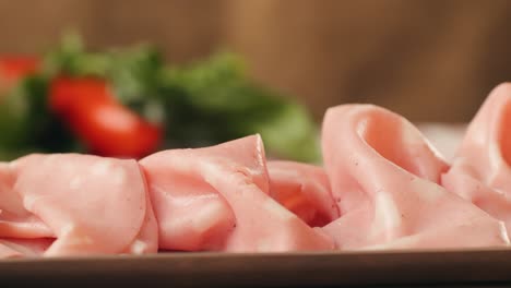ham italian mordatella, man slices of traditional italian antipasti mortadella sausage on a wooden cutting board, close up macro of chicken or turkey jamon, fat breakfast dish.