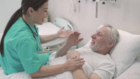 an woman nurse having fun with a patient who lies on a hospital bed