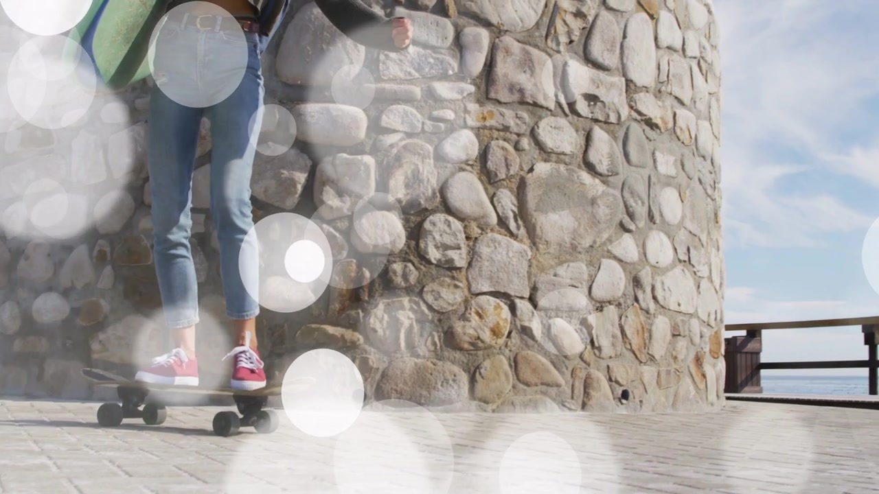 Woman entering left carrying mint board skating past tower with bokeh accenting motion heading surf
