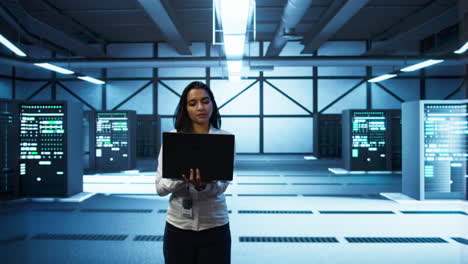 programmer walking in data center, coding on laptop