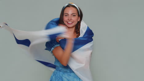 Mujer-Joven-Con-Vestido-Azul-Ondeando-Y-Envolviendo-La-Bandera-Nacional-De-Israel,-Celebrando-El-Día-De-La-Independencia