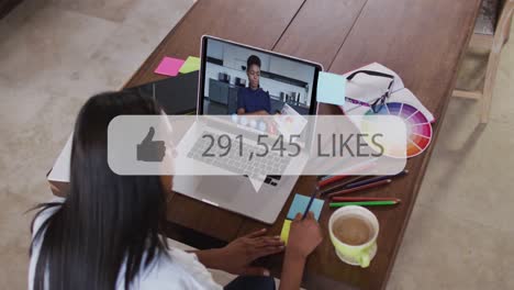 Thumb-icon-and-increasing-likes-against-woman-having-a-video-call-on-laptop-at-office