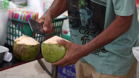 skilled vendor swiftly opening a coconut.