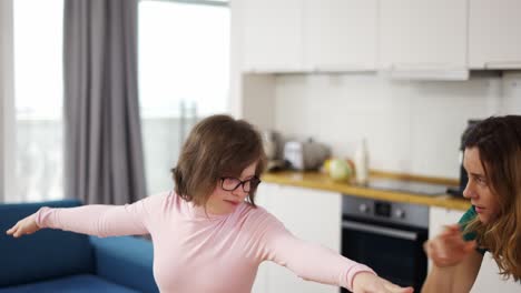 mujer madura positiva con hija discapacitada aprendiendo a mantener el equilibrio de pie en un tapete de yoga