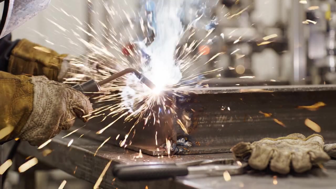 Welding Process: Skilled Worker Uses Torch on Metal Frame, Creating Sparks and Mastering Technique in Industrial Workshop Environment