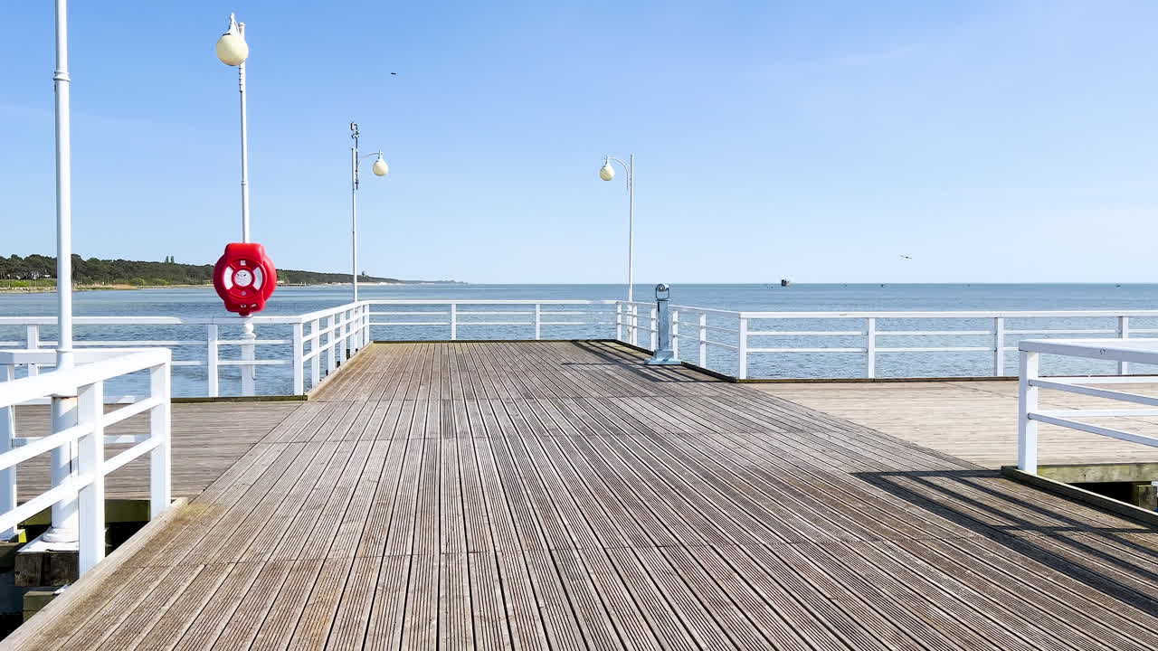 A sunny pier with white railings and lamps