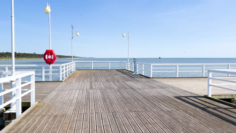 a sunny pier with white railings and lamps