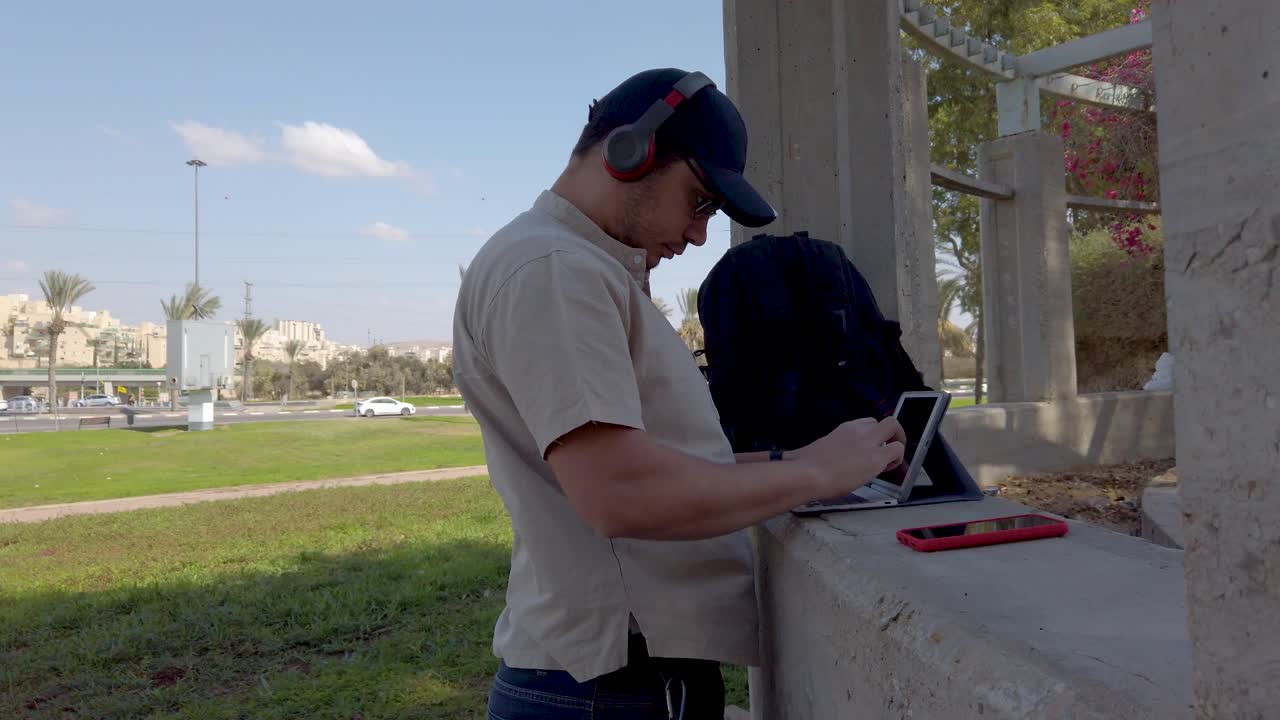 Young man looking at his tablet in a park on a sunny day.
