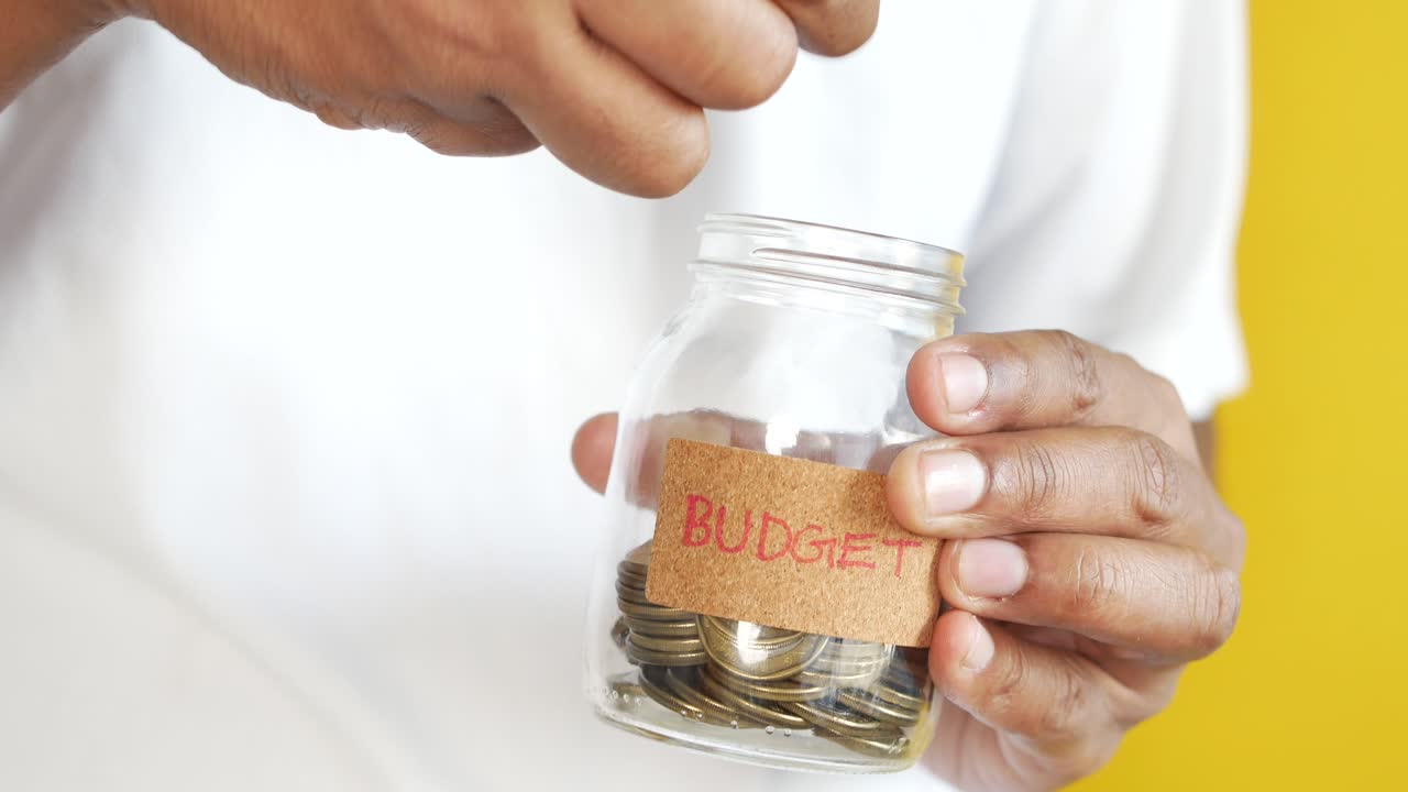 Young man saving coins in a jar white sited