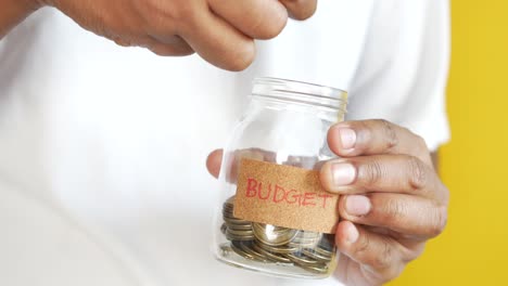 Young-man-saving-coins-in-a-jar-white-sited