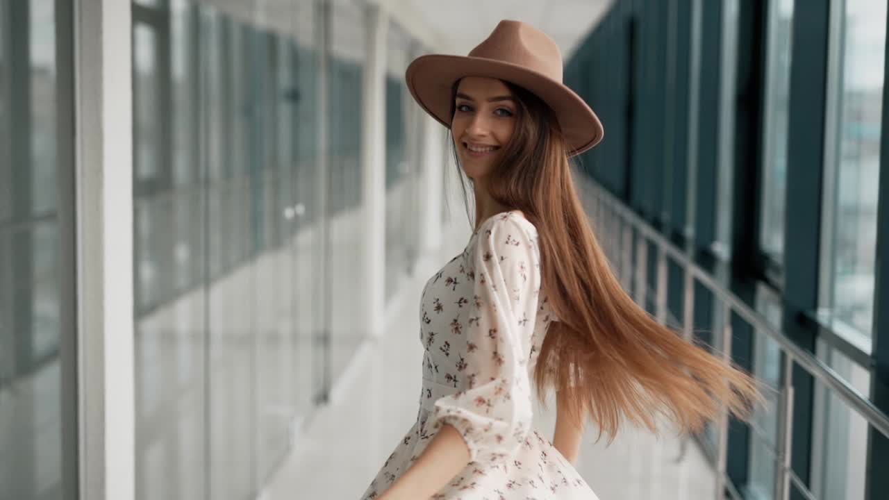 retrato de una chica alegre con un vestido ligero y un sombrero bellamente girando y posando