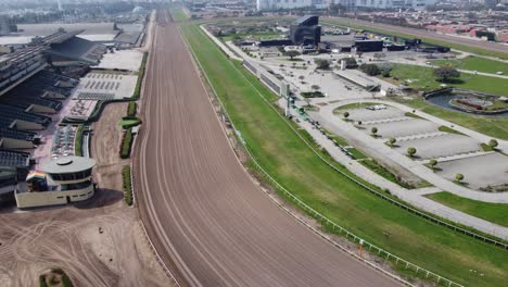video de drones de una pista de carreras de tierra de caballos, con un área de césped verde en el medio también con edificios