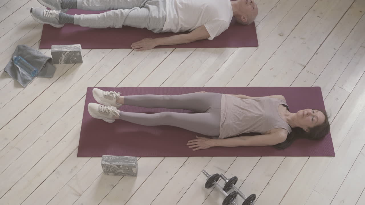 viejos hombres y mujeres haciendo ejercicio en la alfombra de yoga en casa