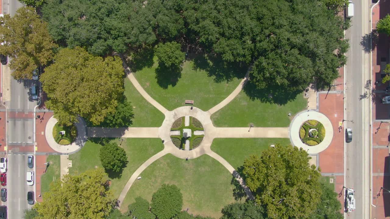 An aerial drone shot above Lafayette Square in the Central Business District of New Orleans, Louisiana. The shot showcases the symmetry of the park design, featuring the bronze statue of Henry Clay