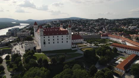 bratislava castle surrounded by greenery and cityscape in slovakia on a sunny day, aerial view