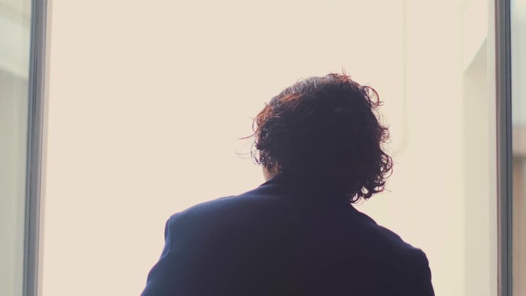 Man opening curtain by window letting soft daylight in