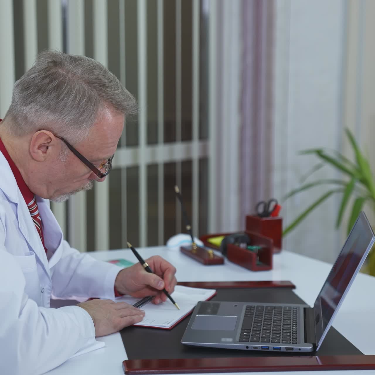 Doctor chatting with patients online, using laptop at his workplace. Telemedicine concept