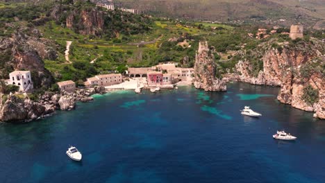 aerial pullback reveals tonnara di scopello and famous sea stacks