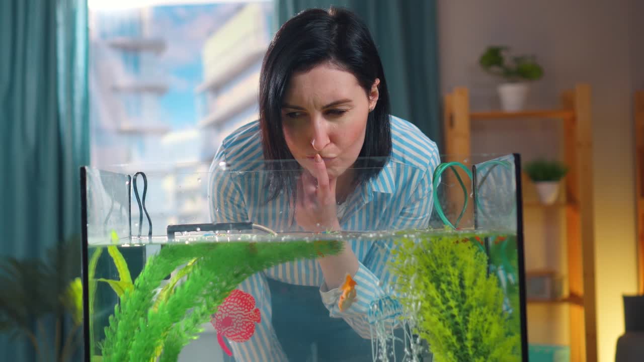 집 에 있는 금고기 수족관 을 둘러싼 혼란 스러운 젊은 여자