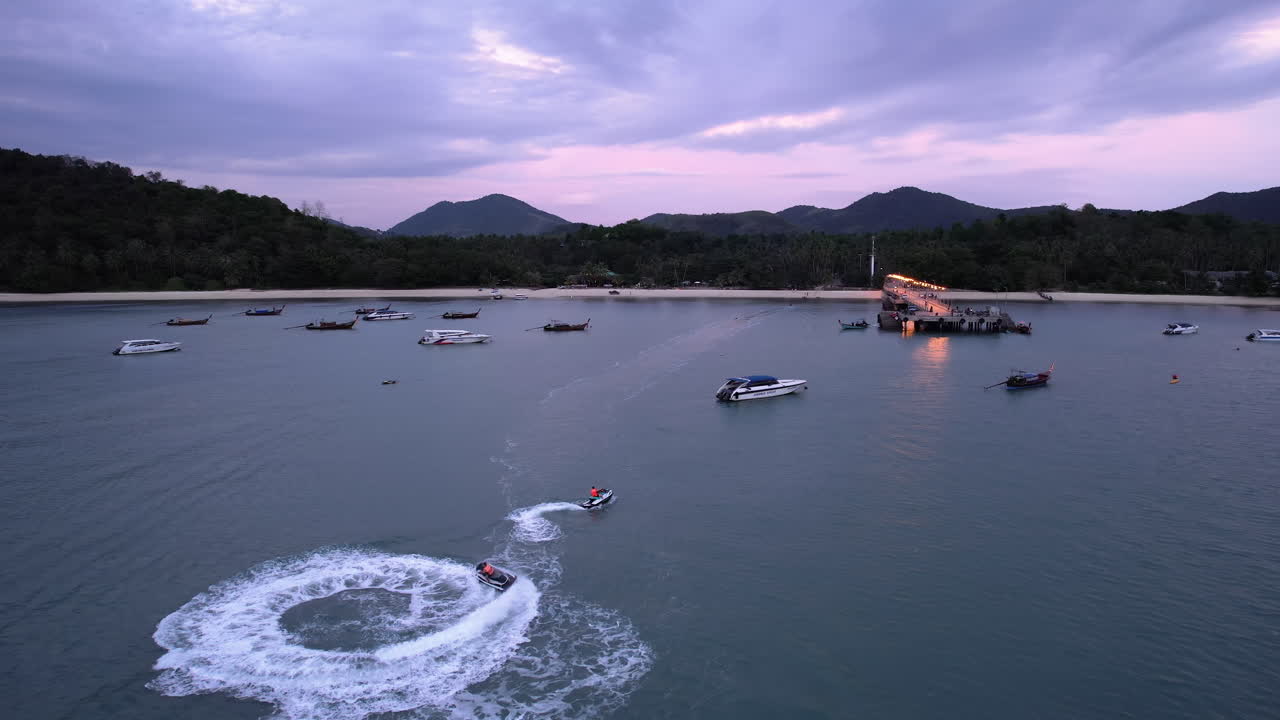 jet skis haciendo rosquillas en la isla de koh yao yai, al anochecer en tailandia - vista aérea